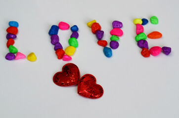 Letters from multi-colored stones on a white background. Romantic relationship concept