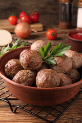 Tasty cooked meatballs with parsley on wooden table