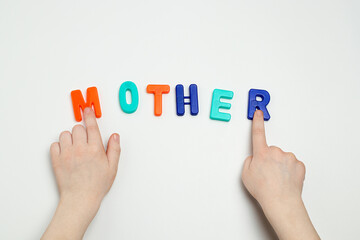 The child's hands and the word mother made of multicolored letters