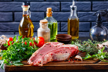 porterhouse beef steak with herbs, spices.  beef steak on a rustic wooden board with bottles and a brick wall at the background