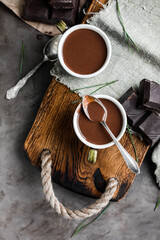 Two cups of hot chocolate on a wooden tray with vintage spoons and chocolate pieces. View from above. Sweet hot drink.