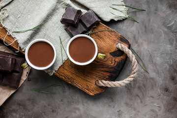 Two cups of hot chocolate on a wooden tray with vintage spoons and chocolate pieces. View from above. Sweet hot drink.
