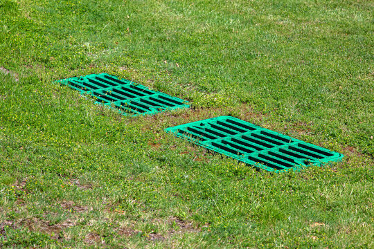 catch basin grate drainage on the lawn with green grass septic tank cover, two rectangular green eco hatches sump cesspool drainage system environment design, nobody.