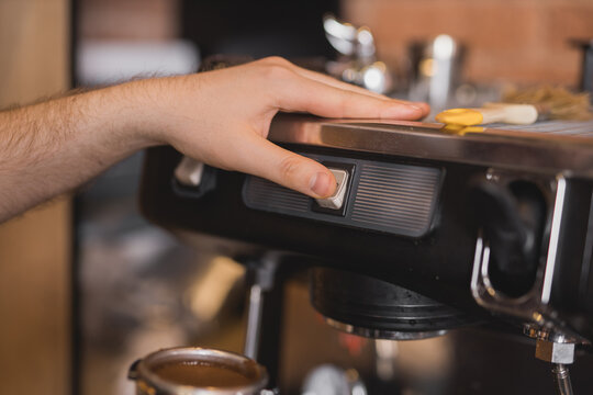 Barista pressing button on coffee machine