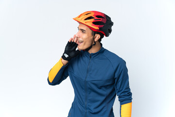 Young cyclist man isolated on background shouting with mouth wide open to the side