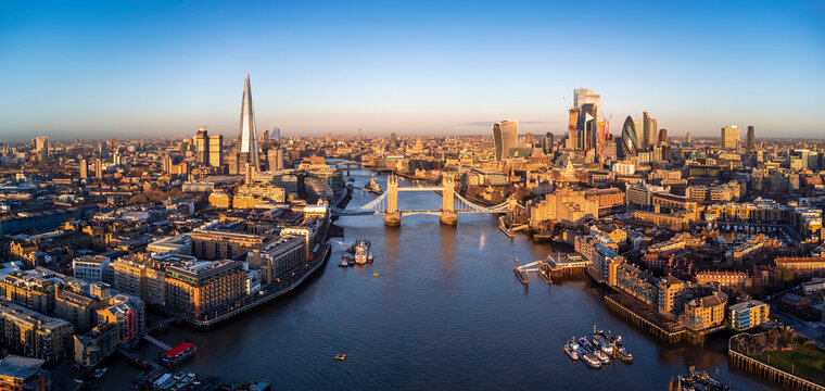 Panoramic aerial view of the skyline of London, England, with Tower Bridge and the skyscrapers of the City in golden sunrise light © moofushi