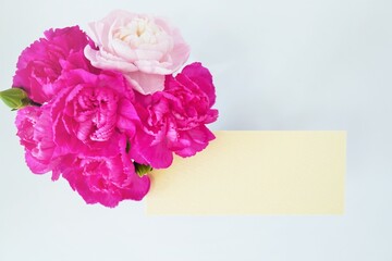 赤とピンク色のカーネーションの花を添えた母の日のグリーティングカードのモックアップ