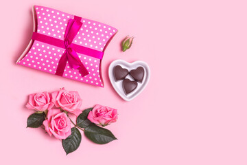 Pink beautiful roses, chocolate and gift box on pink background. Mothers day, Valentines Day