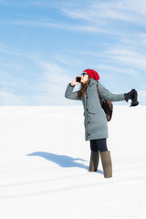 Fototapeta na wymiar Young woman talking on her smart phone while on vacation in the snow