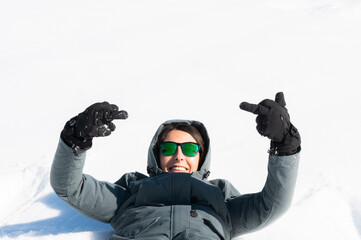 Cute young girl lying in the snow looking into the camera