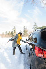Woman getting into her car on a sunny, snowy winter day