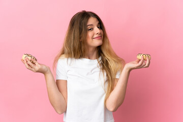 Young blonde woman isolated on pink background holding donuts