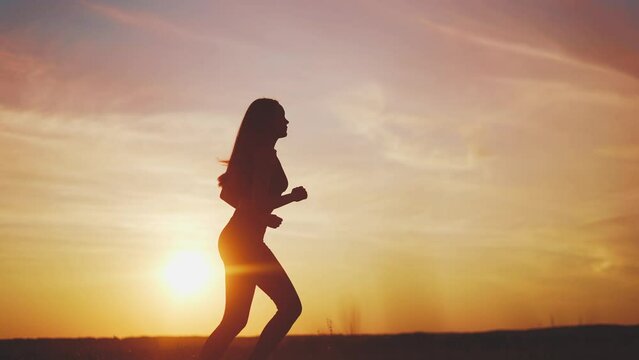 woman runner. girl silhouette running fast a outdoor sports sunlight. fitness marathon in the park running. free woman run runs in nature side view. training goal achievement success concept
