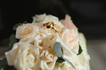 gold rings and a beautiful bridal bouquet of roses on the background. details, wedding traditions. close-up, macro