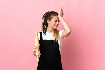 Young blonde woman holding a rolling pin isolated on pink background has realized something and intending the solution