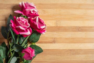 Bouquet of pink plastic roses on a wooden table