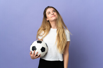 Young blonde football player woman isolated on purple background and looking up