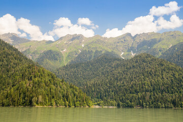 Beautiful mountain lake in nature valley at summer.Beautiful mountain Lake Ritsa. Lake Ritsa in Caucasus Mountains, in Abkhazia, Georgia, surrounded by mixed mountain forests and subalpine meadows.
