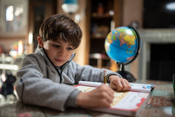 Little boy in tracksuit does homework at home