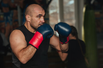 A male athlete of a strong physique, a boxer stands in a boxing stance and is ready to strike. He...