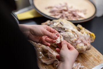 Frau zerlegt ein Huhn mit ihren Händen