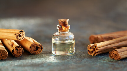 A bottle of aromatherapy essential oil with Ceylon cinnamon sticks - obrazy, fototapety, plakaty