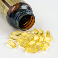 Gelatin capsules with omega-3 and glass bottle on a light background