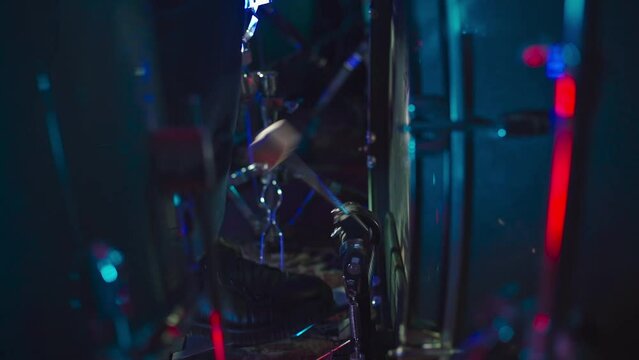 The drummer kicks the bass drum with a pedal