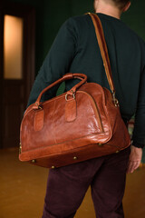 close-up photo of orange leather travel bag on mans shoulder