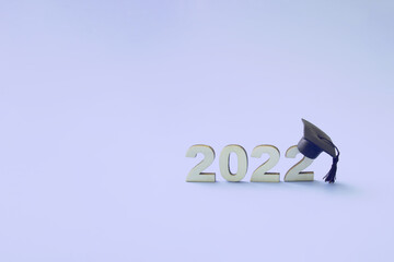 Graduation 2022 wearing graduate hat on wooden number 2022 on very peri tredy color background,...