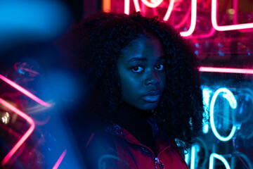portrait of an African American young woman in sunglasses isolated on a neon lightbackground 