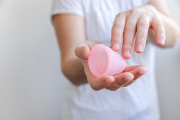 Woman hand holding pink menstrual cup isolated on white background. Woman modern alternative eco gynecological hygiene in menstruation period. Container for blood in girl hand