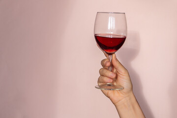 Woman hand holding glass of red wine, natural sunlight and abstract shadow. retro styled photography 