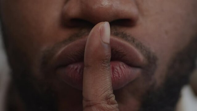 Extreme close up of a quite sign using lips and forefinger