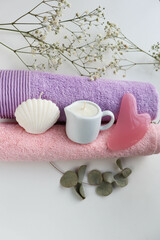 spa theme. a set of towels in pastel colors, a massage candle in a white jug and gua sha massager