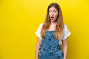 Young caucasian woman isolated on yellow background doing surprise gesture while looking to the side