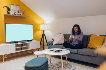 Hispanic woman using smartphone while sitting on the couch at home