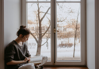 woman reading at home at the window