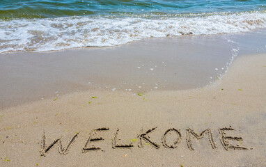 Handwritting inscription welkome word on tropical sandy beach, travel concept card for holidays