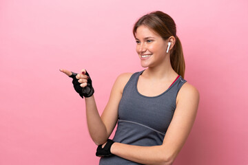 Young sport caucasian woman isolated on pink background pointing finger to the side and presenting a product