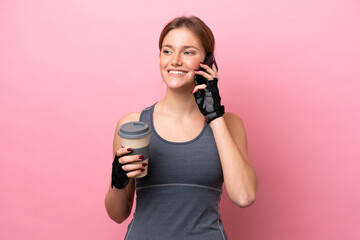 Young sport caucasian woman isolated on pink background holding coffee to take away and a mobile