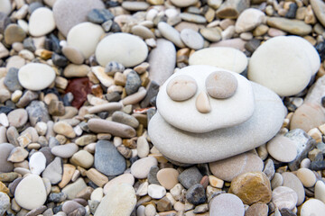 Fototapeta na wymiar The figure is laid out of pebbles on the beach.