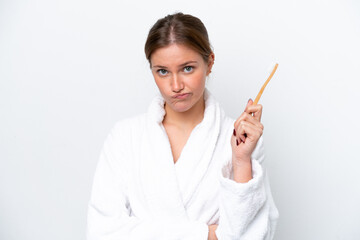 Young caucasian woman brushing teeth isolated on white background with sad expression