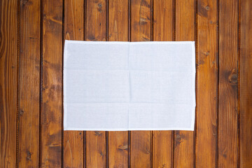 Top view of white napkin or dish towel on empty wooden table