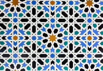 Old Islamic tiles (also known as zellige or azulejos) with traditional geometric patterns decorating a wall of the Nasrid Palaces inside the Alhambra. Granada, Andalusia, Spain.