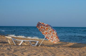Beach umbrella from the sun and sunbeds are on the beach against the blue sea, sunbeds are towels