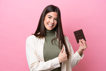 Young Brazilian woman with chocolat isolated on pink background giving a thumbs up gesture