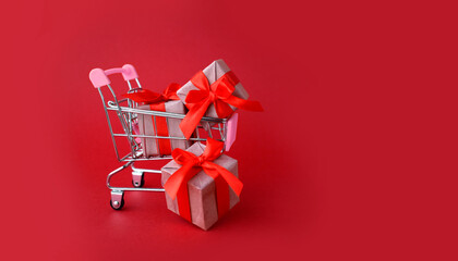 Greeting minimal concept for Valentines day sale. Shopping cart with gifts on red background. Mock up retail banner for Valentines day, Mothers day, Women day or Black Friday sale.