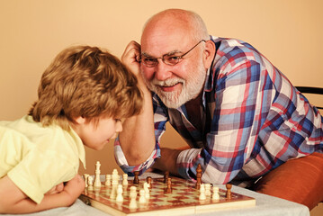 Grandson and grandfather playing chess. Childhood and board games, family and generation concept.