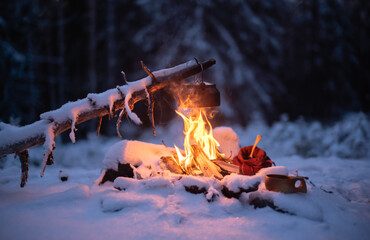 Making coffee over a campfire in a snow-covered forest landscape